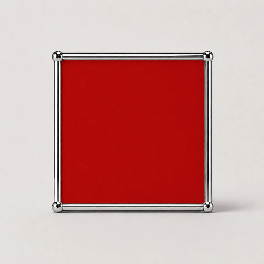A square ruby red plaque or sign with a polished silver metal border and corner caps, shown against a neutral light gray background.