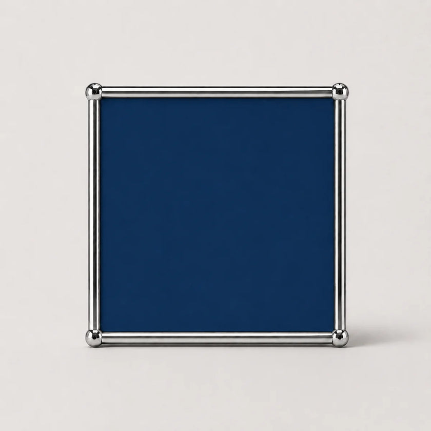 A square steel blue plaque or sign with a polished silver metal frame and corner protectors, shown against a light gray background.