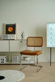 Brown wassily rattan chair with wicker backrest in a minimalistic room with a shelf and decorative items.