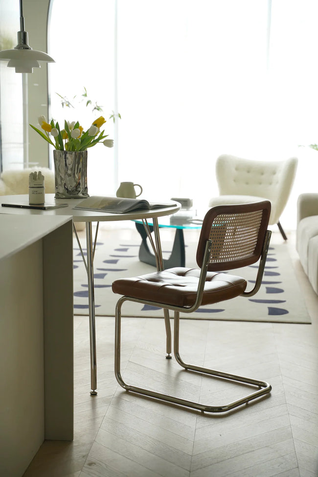 Modern dining room with a wassily rattan chair, table, and decor elements.