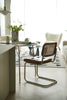 Modern dining room with a wassily rattan chair, table, and decor elements.