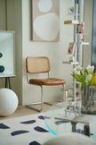 Modern interior with a dining room rattan chair, round table, and decorative elements.
