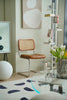 Modern interior with a dining room rattan chair, round table, and decorative elements.