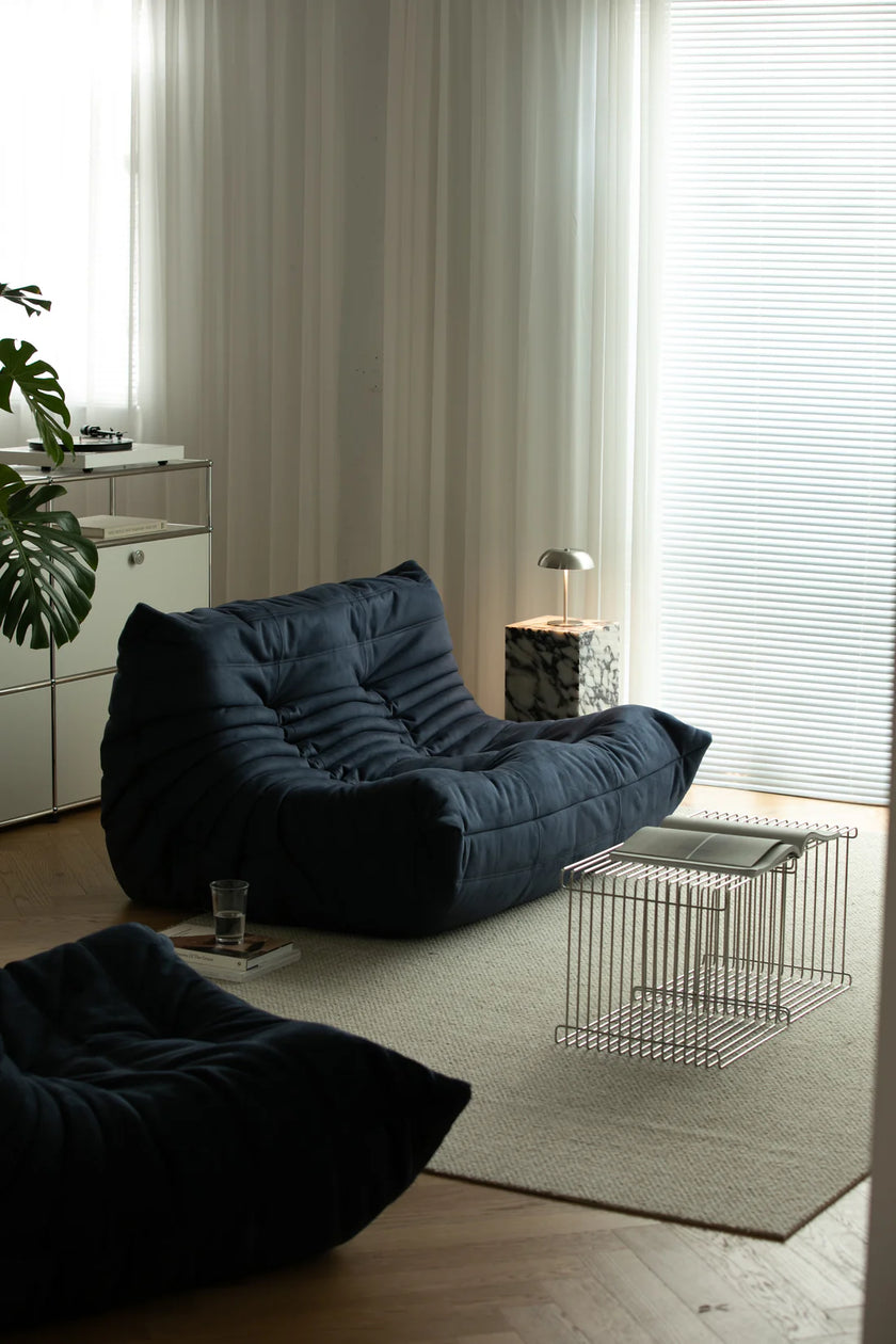 Modern living room with dark blue love seat sofa and a small table.