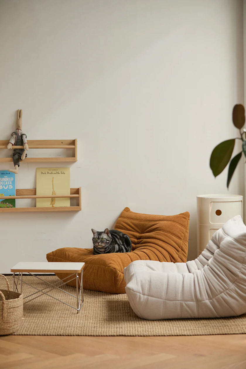 Cozy living room with a white kids sofa, brown corduroy sofa, and wooden shelf.