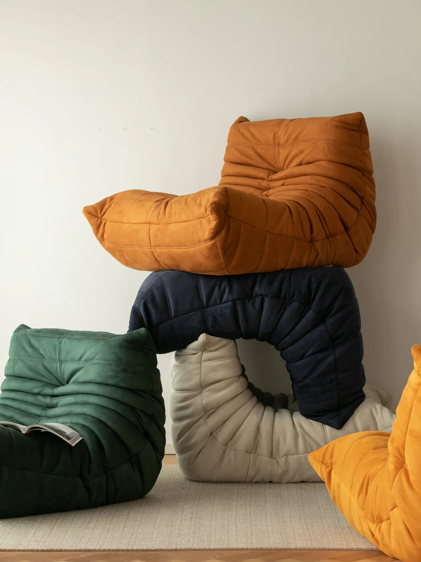 Stack of colorful modern sofa on a light wooden floor against a white wall