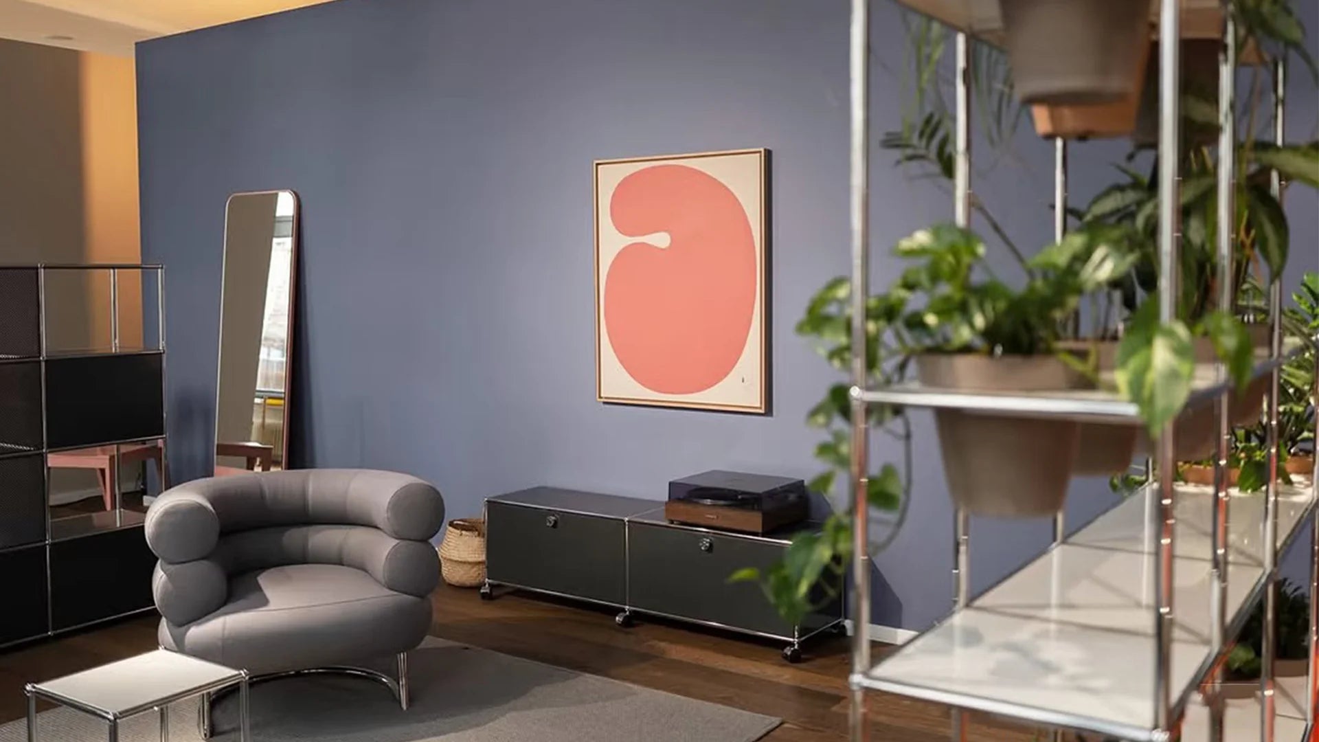 Modern living room with a gray armchair, TV, and decorative wall art.