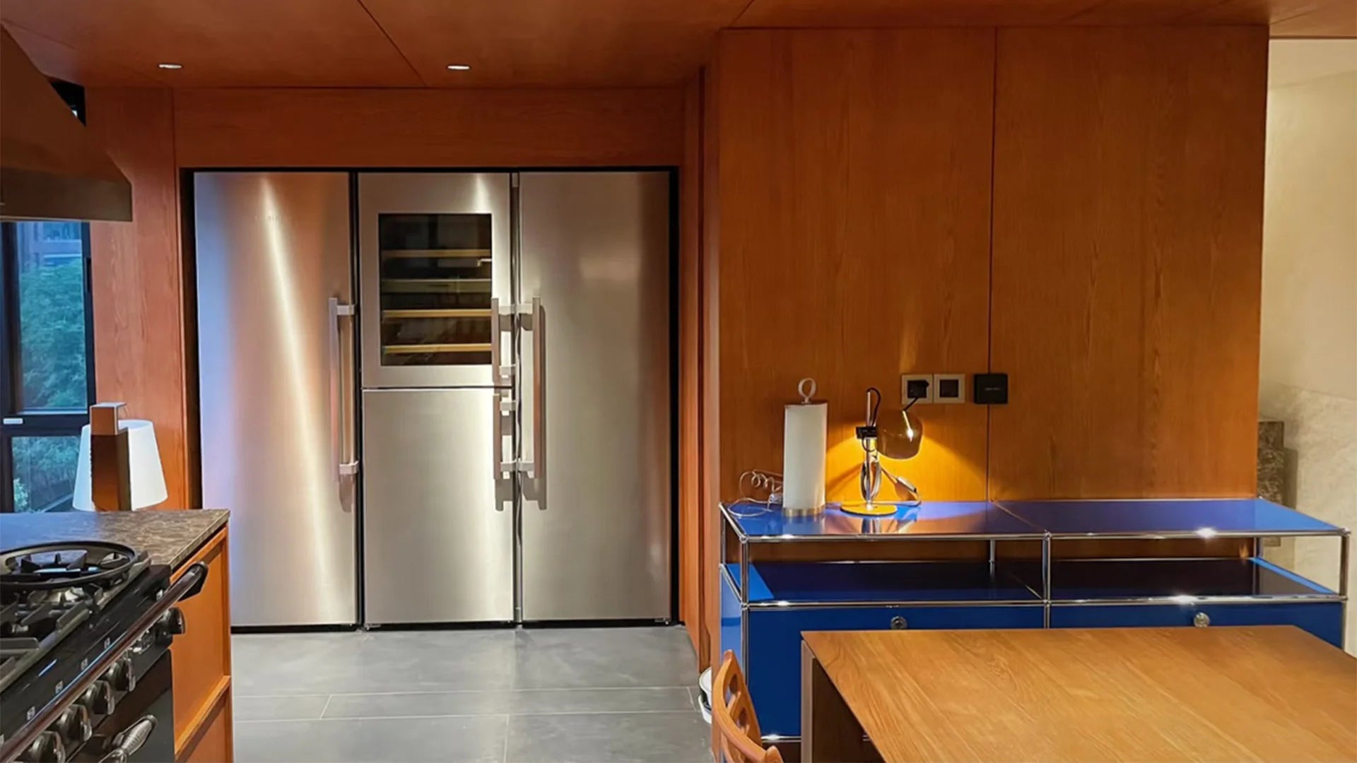 Modern kitchen with stainless steel refrigerator, wooden cabinets, and blue countertops.