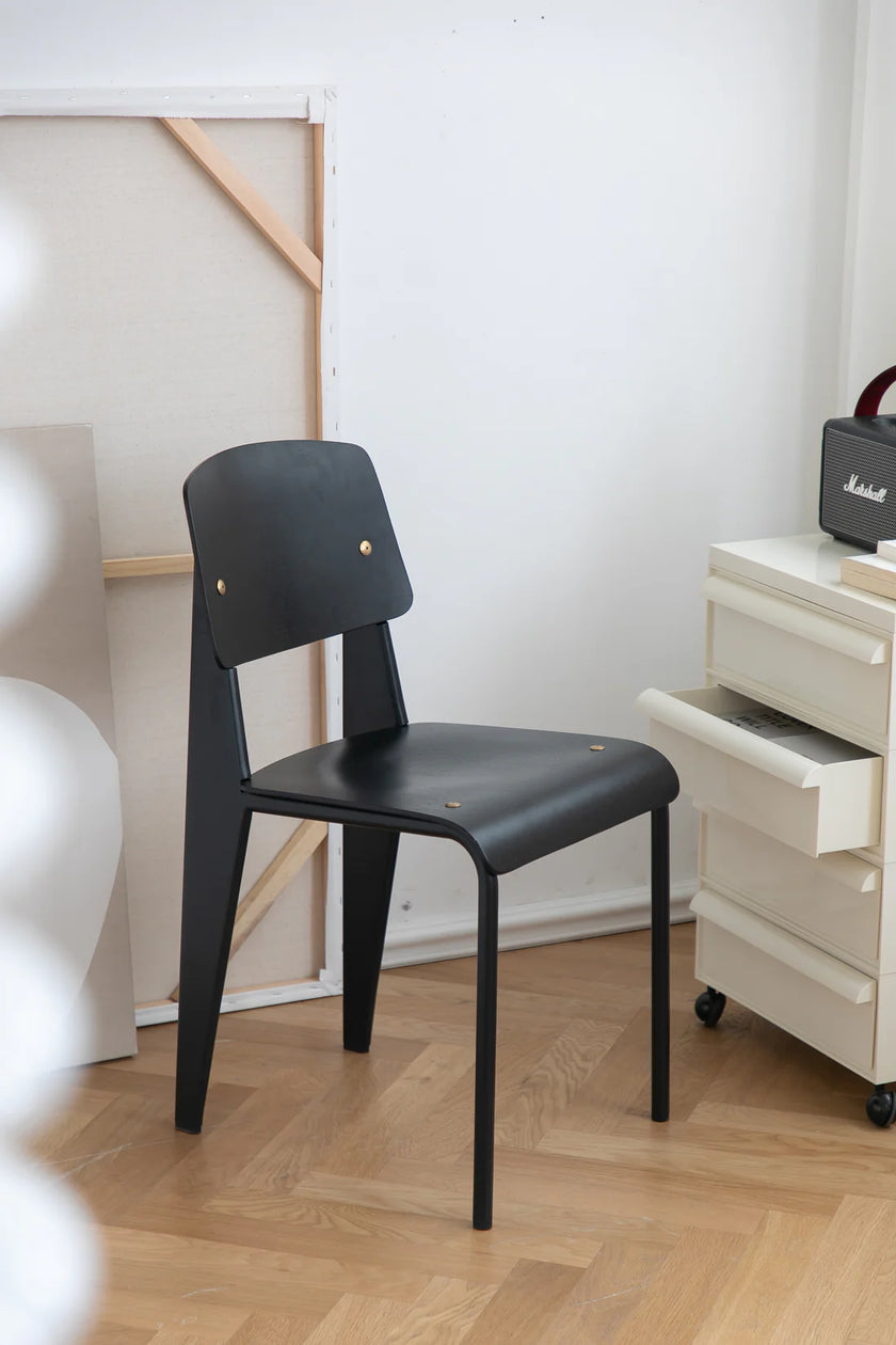 Black wooden living room chair in a room with a white wall and wooden floor.