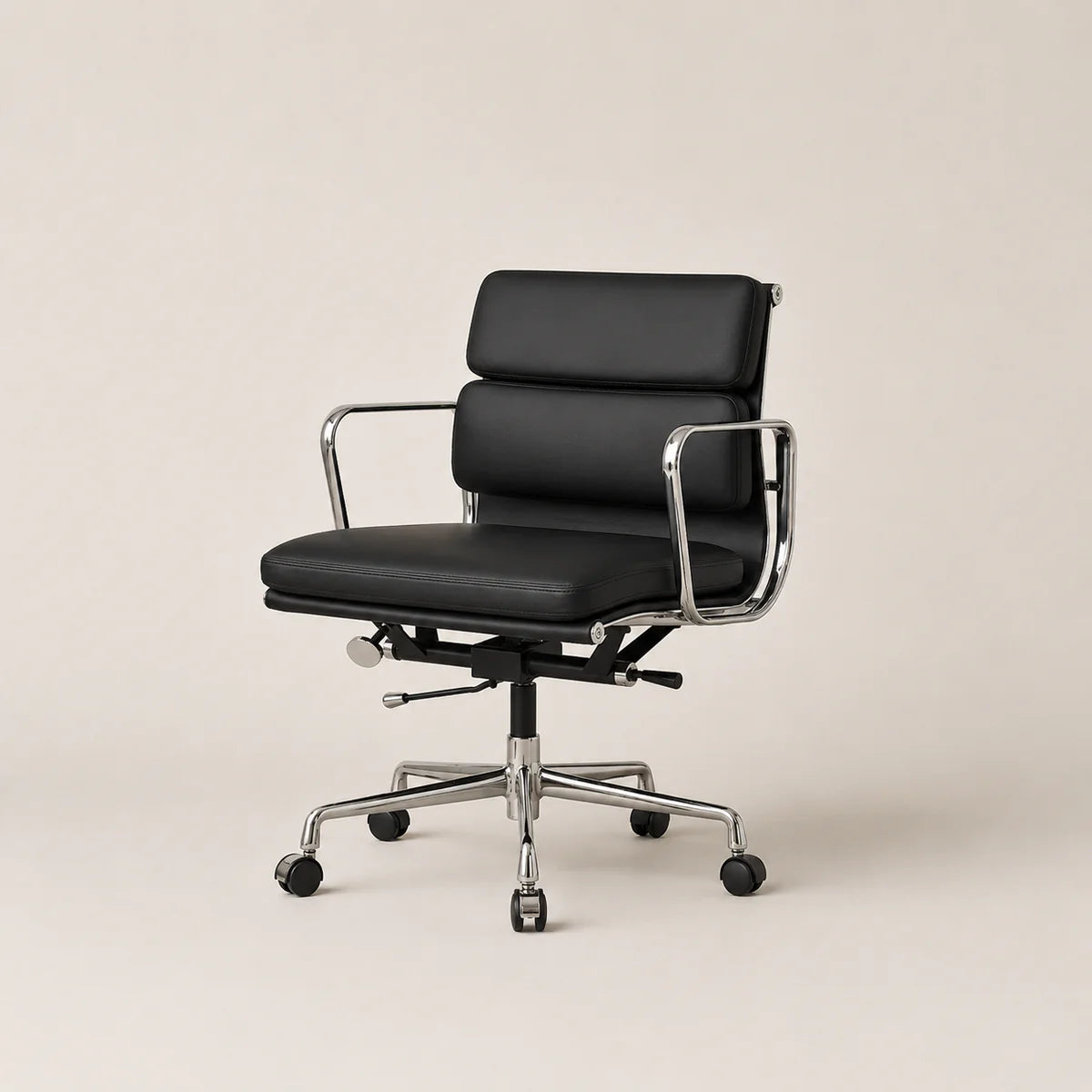 A modern black leather office chair with a chrome metal frame and five-wheel base, photographed against a solid light beige background.