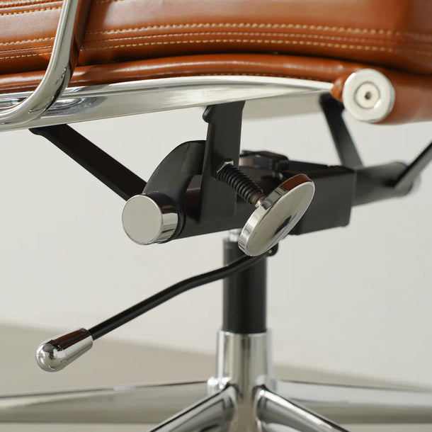 Close-up of a brown leather chair with metal frame and adjustable mechanism.