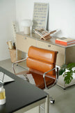 Modern office setup with a brown leather chair, desk, and whiteboard.