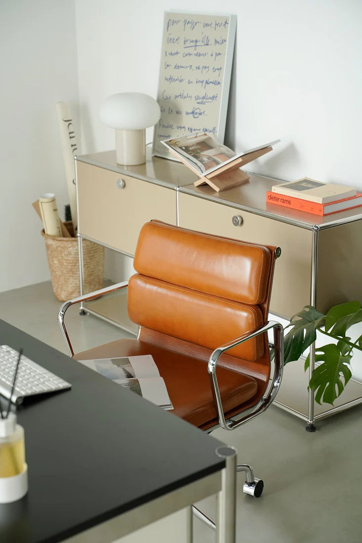 Modern office setup with a brown leather chair, desk, and whiteboard.