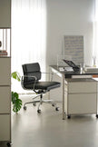 Modern office desk with black chair and whiteboard in a bright room