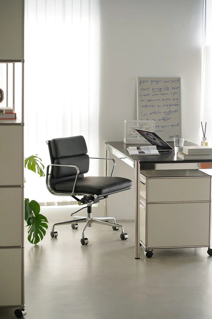 Modern office desk with black chair and whiteboard in a bright room