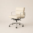 An off-white leather office chair with a chrome metal frame and five-star wheeled base, photographed against a solid light beige background.