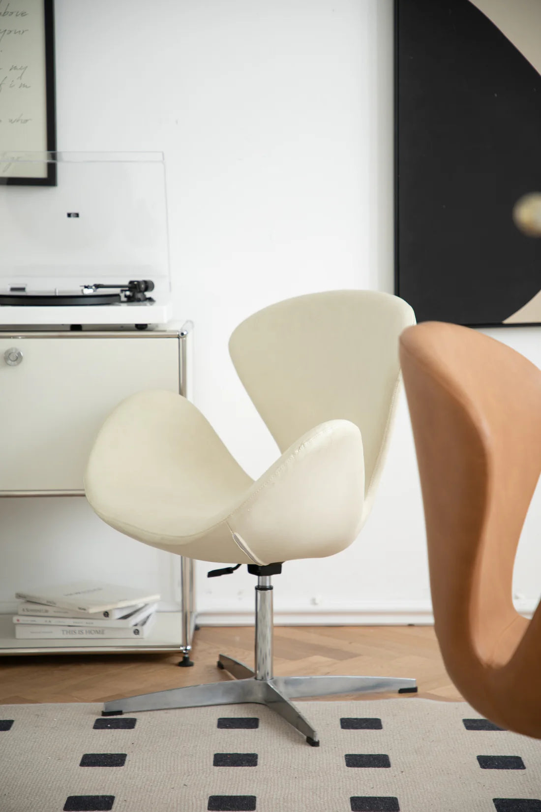 Modern leather swivel desk chairs in a room with a record player and abstract art on the wall.