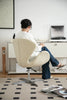 Lady sitting on a beige desk chair in an office setting with a desk and computer.