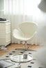 White leather swivel chair in a room with a glass coffee table and white curtains.