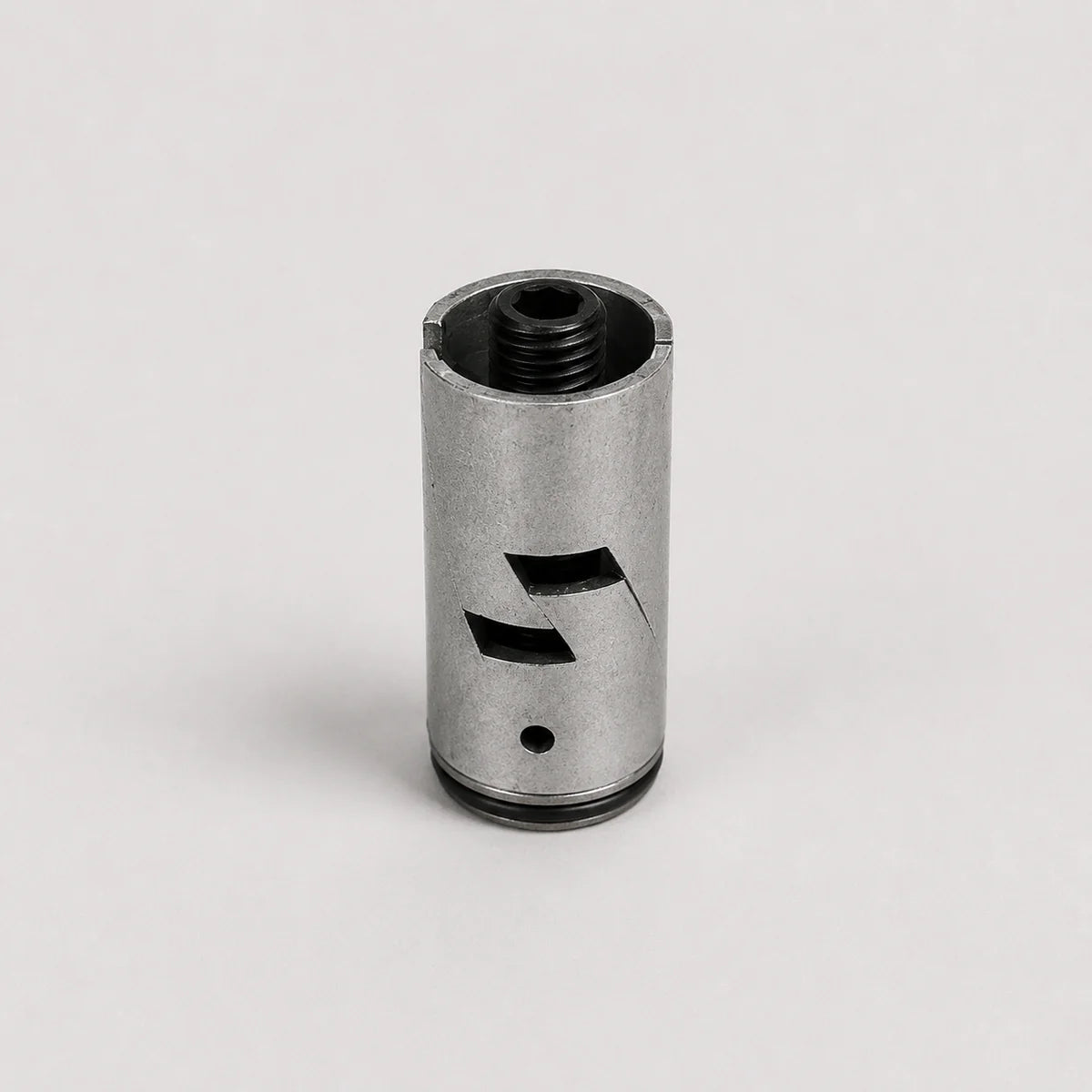 A metallic silver cylindrical component with black threaded openings and cutout details, photographed on a clean light gray background.