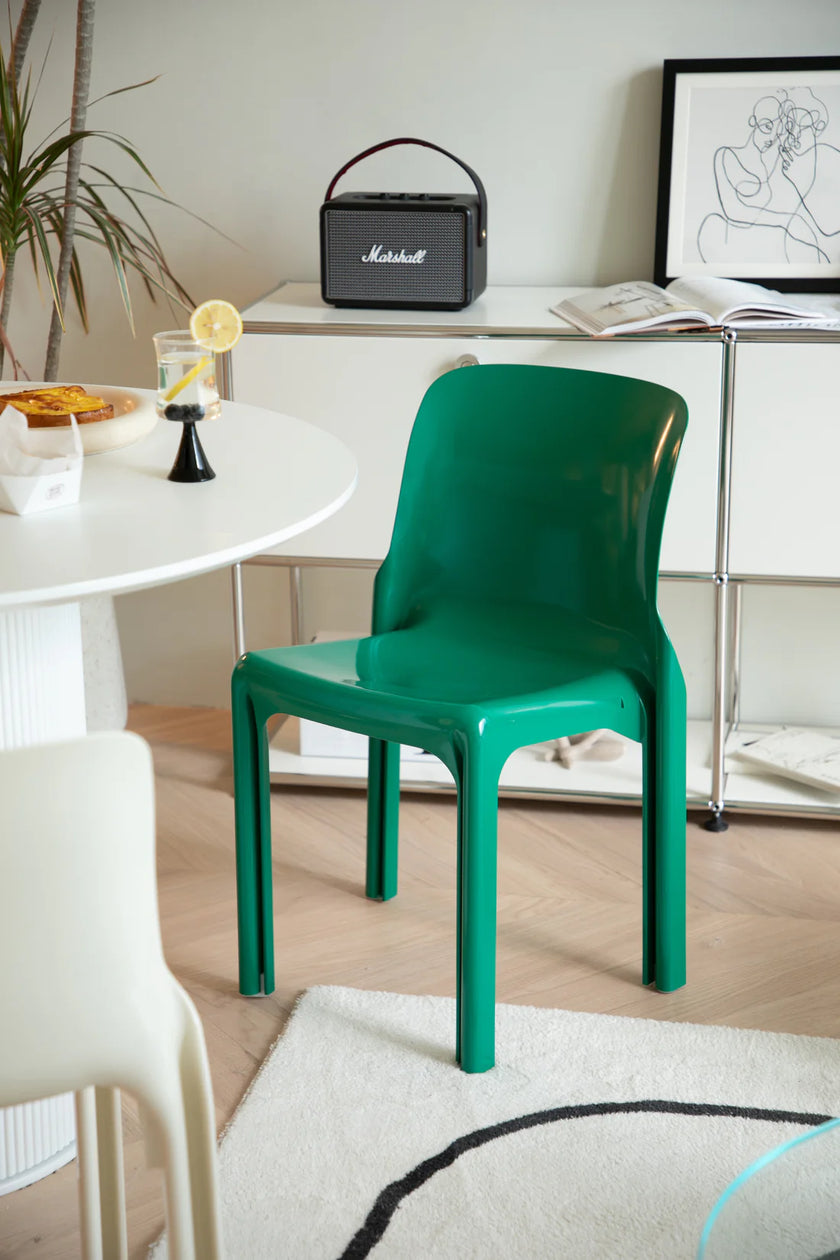 Green dining room chair in a room with a white table, plant, and framed picture.