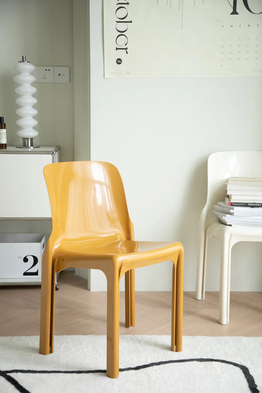 Yellow plastic chair in a room with a white wall and decor elements.
