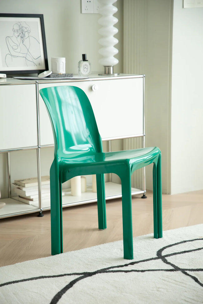 Green living room chair in a room with a white cabinet and decorative items.