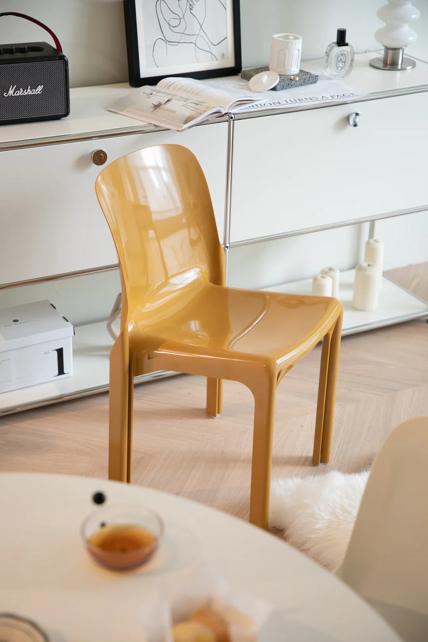 Yellow plastic chair in a room with a desk and decor items.