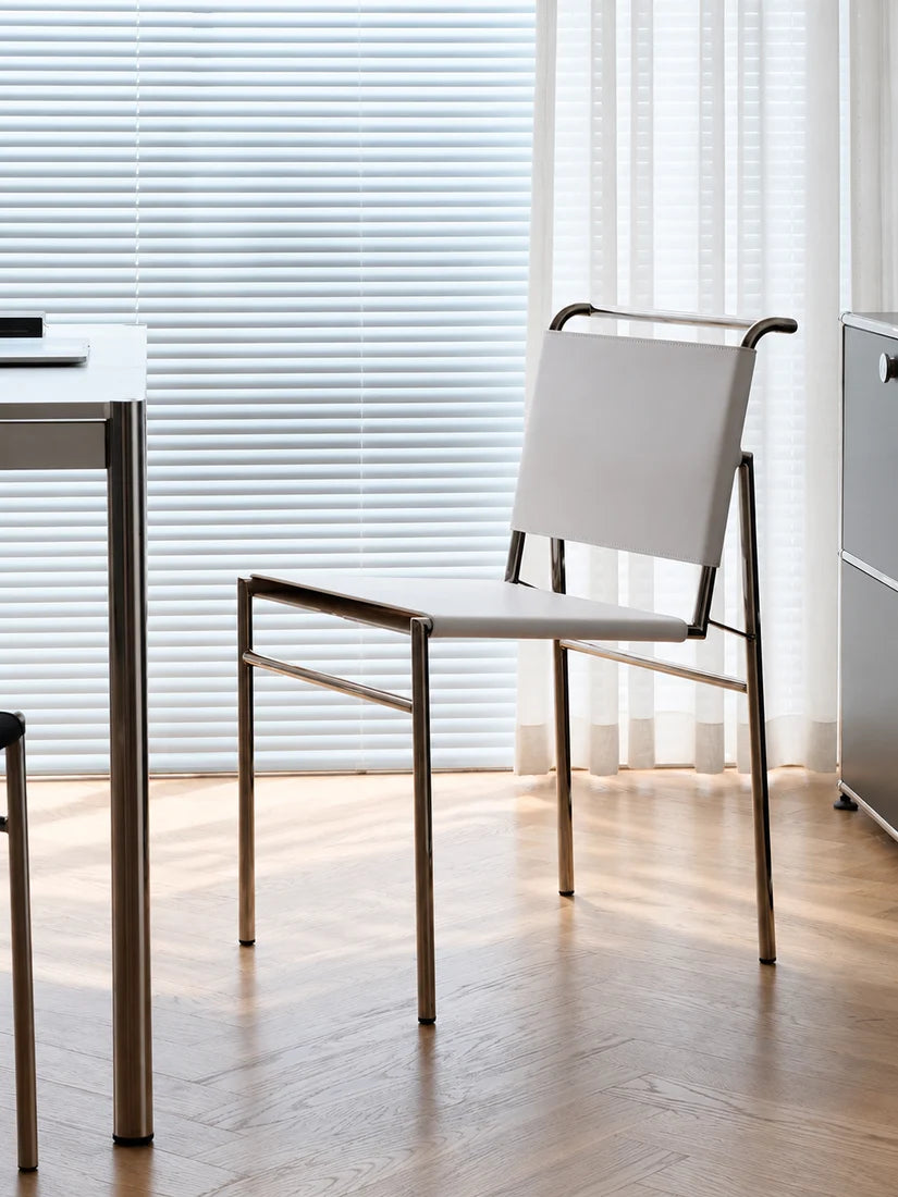 A modern white and gold metal chair with a woven backrest, positioned in a bright, contemporary home office next to a white desk.