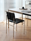 A modern black and gold metal chair with a woven backrest, positioned in a bright, contemporary home office next to a white desk.