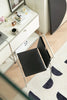 Modern office desk with a black dining room chair, laptop, and decorative items on a patterned rug.