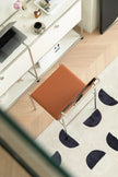 White desk with a brown office chair in a room with a patterned rug