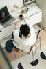 Lady sitting leather office chair at a desk with a laptop, holding a cup of coffee.