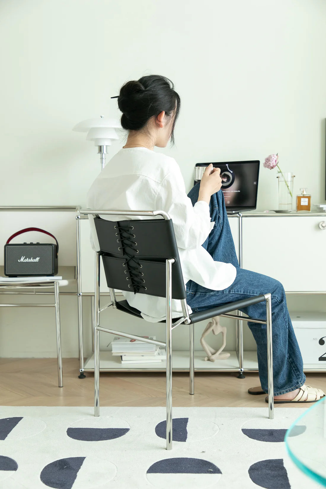 Lady sitting office chair at a desk using a computer in a home office setting.