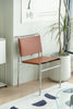 Brown living room chair with metal frame in a room with a plant and calendar on the wall.