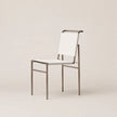 A modern dining chair with a white sling fabric seat and backrest, supported by a slim brushed metal frame, shown against a solid light beige background.