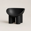 A minimalist black molded PE plastic stool with a wide, rounded seat and four cylindrical legs, shown against a solid light beige background.