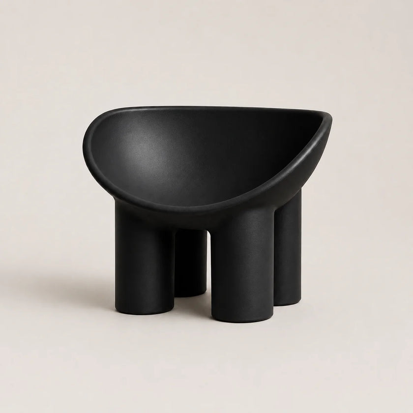 A minimalist black molded PE plastic stool with a wide, rounded seat and four cylindrical legs, shown against a solid light beige background.