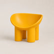 A bright yellow molded PE chair with a rounded, bowl-like seat and four cylindrical legs, photographed on a clean light beige studio background.