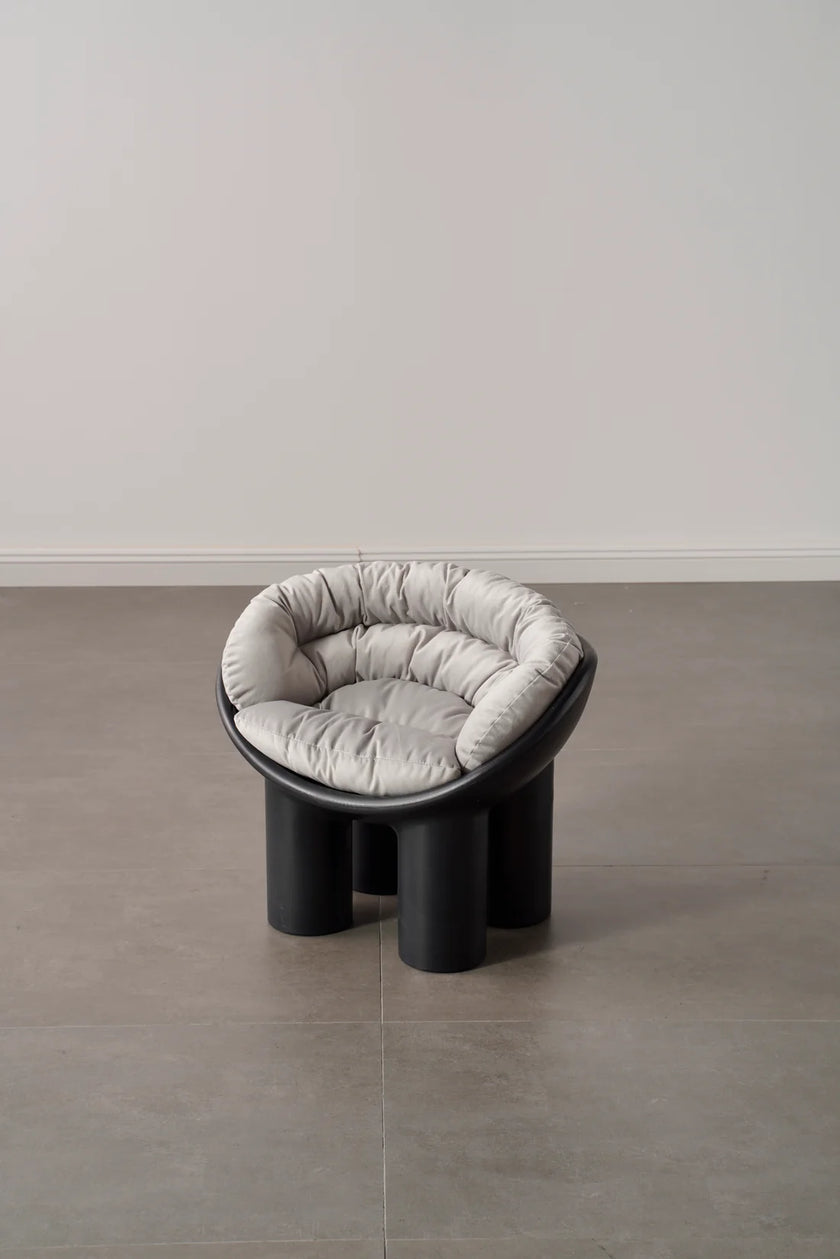 Modern kids plastic black stool with cushioned seat and backrest on a plain floor and wall background