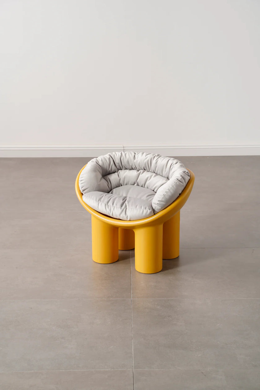 Yellow kids plastic stool with a gray cushion on a gray floor.