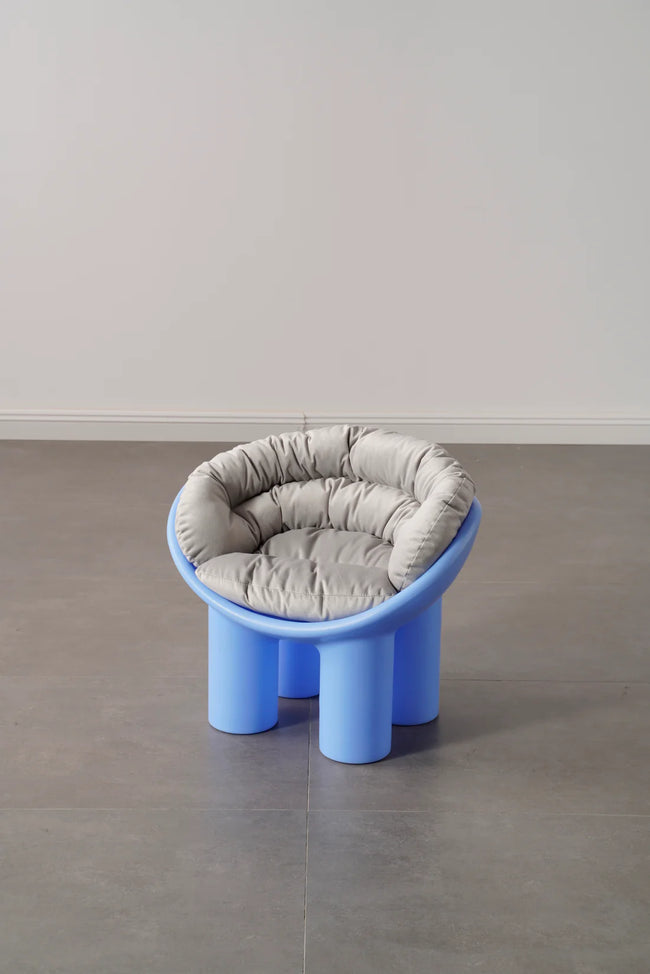 Blue plastic kids toys stool with a gray cushion on a plain floor and wall background