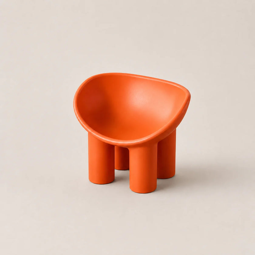 A small modern orange PE stool with a rounded, bowl-like seat and four cylindrical legs, photographed on a plain warm light gray background.