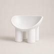 A minimalist white PE molded chair with a wide, rounded seat and four cylindrical legs, photographed against a solid light beige background.
