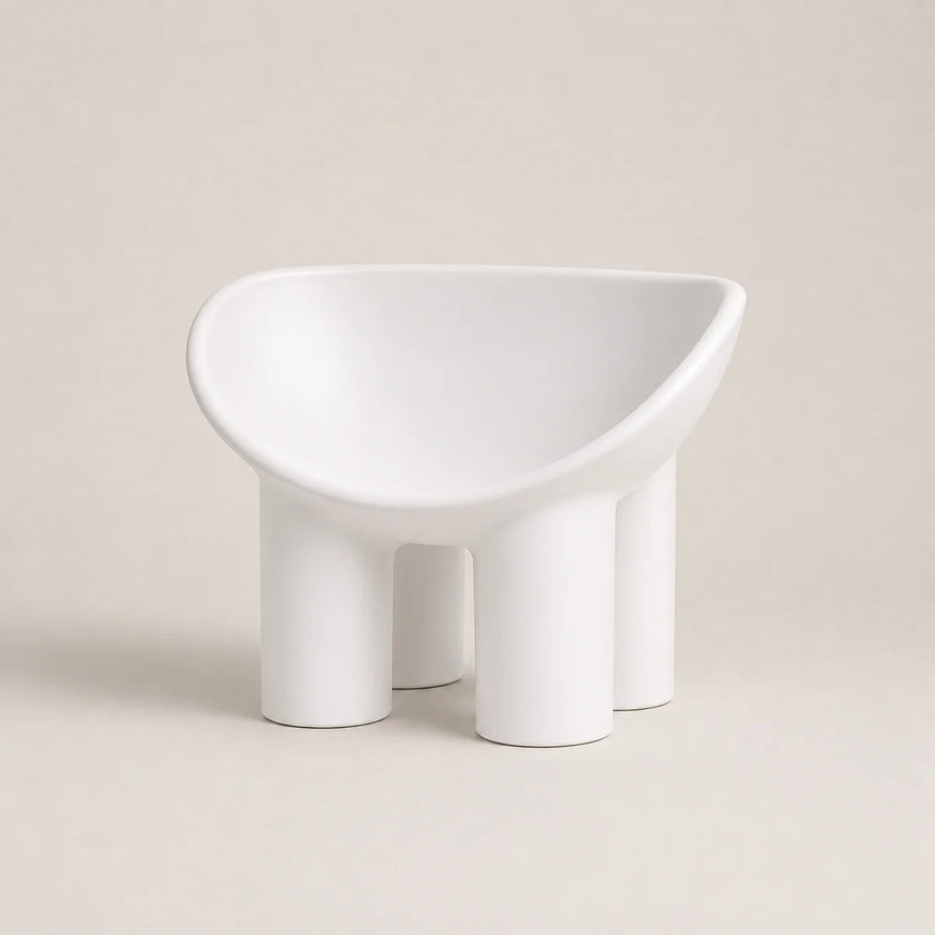 A minimalist white PE molded chair with a wide, rounded seat and four cylindrical legs, photographed against a solid light beige background.