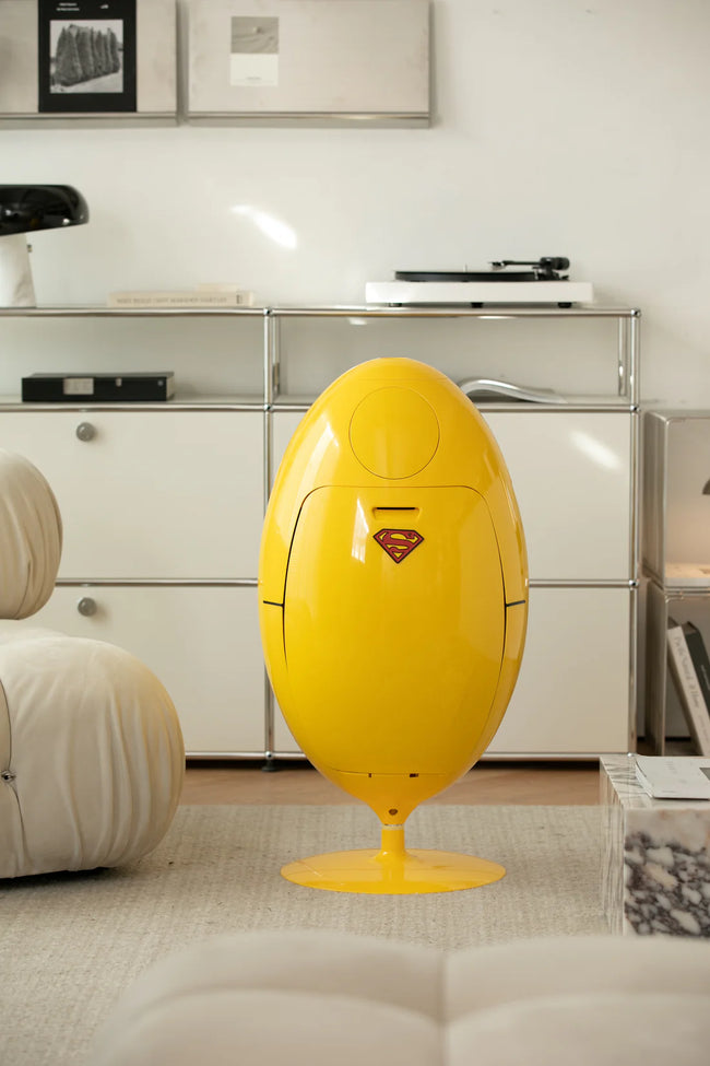 Yellow egg-shaped recycle bin with Superman logo in a modern living room.