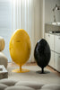 Yellow and black egg-shaped recycle bin in a living room setting.