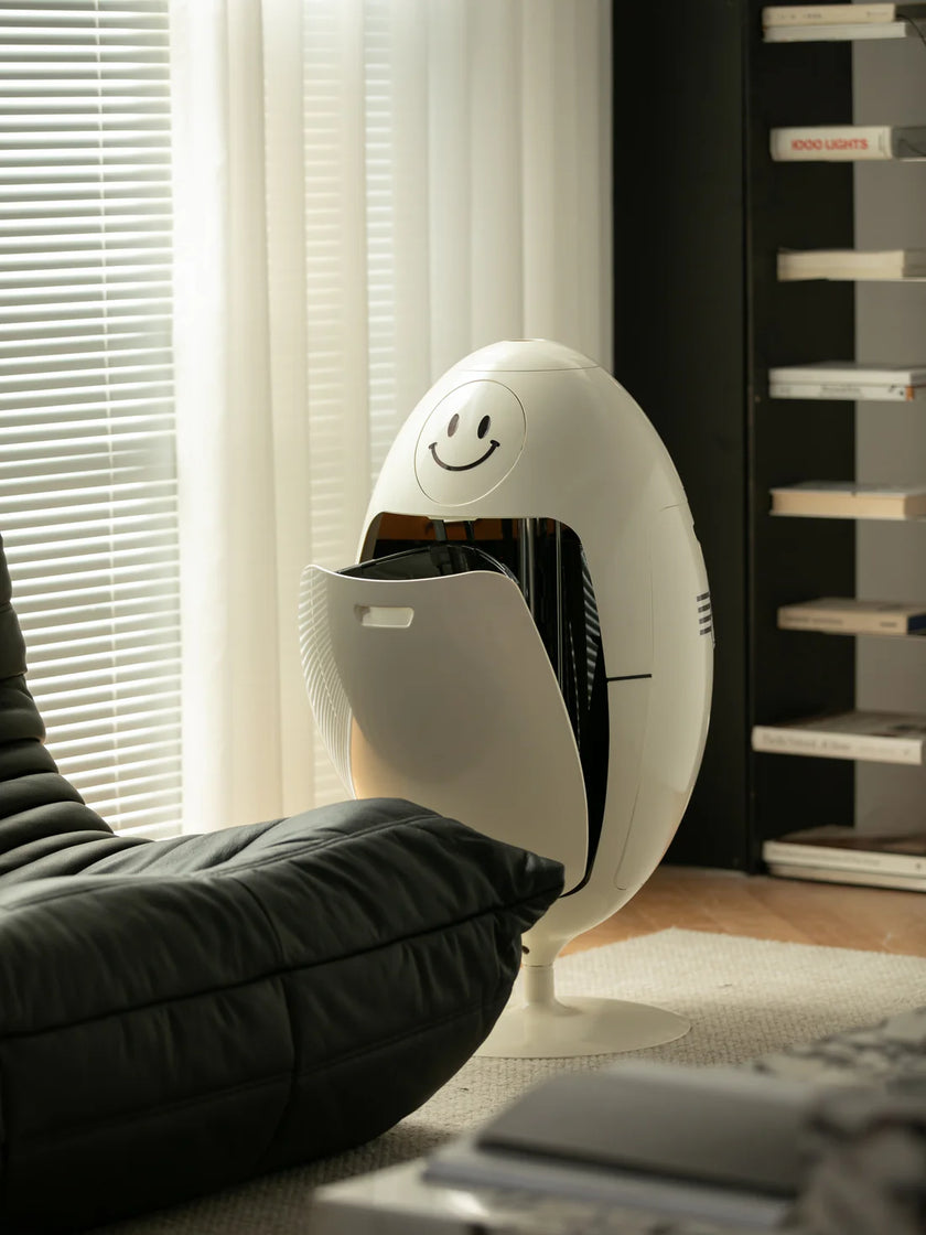 White house recycle bin with smiley face design in a room with curtains and a shelf.