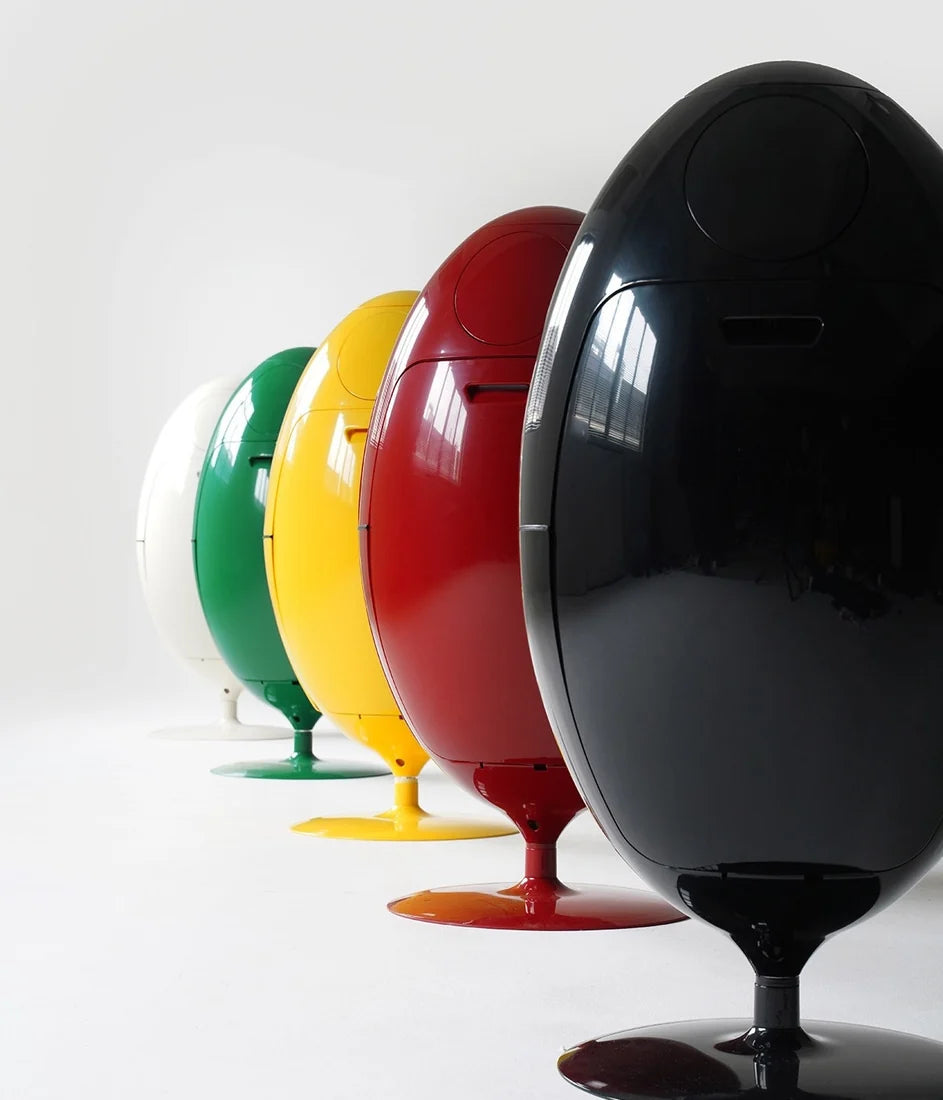 Five glossy egg-shaped storage containers or cabinets in white, green, yellow, red, and black, arranged in a diagonal row on a clean white studio background.
