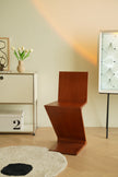 Wooden chair in a room with a light-colored wall, a small table with a vase of flowers, and a lamp.